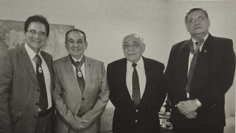 Foto preta e branca de homem de terno e gravata e pessoas ao fundo O conteúdo gerado por IA pode estar incorreto.