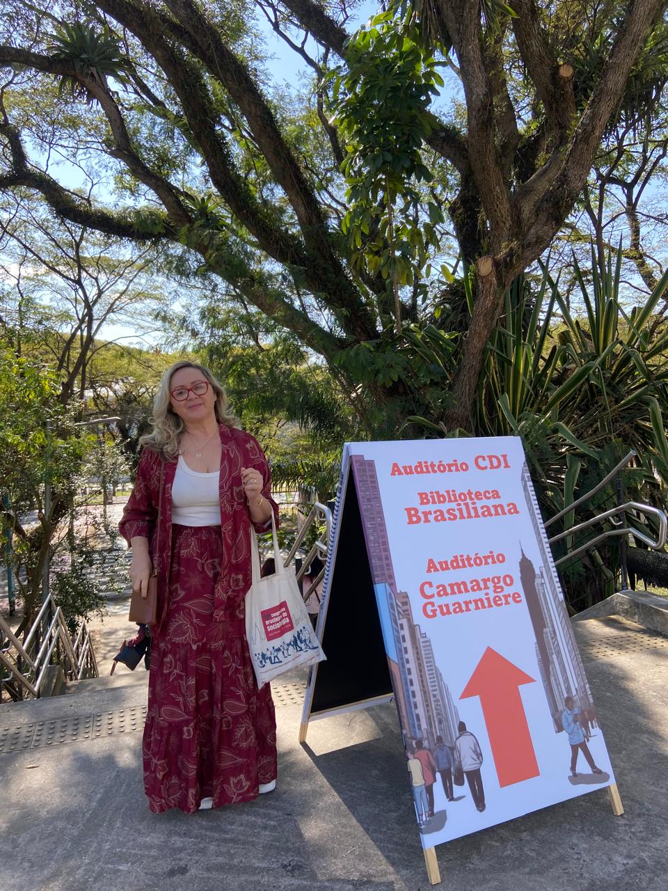 Mulher ao lado de placa O conteúdo gerado por IA pode estar incorreto.
