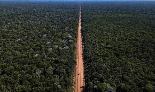 Imagem aérea da BR-319 cortando uma área de floresta amazônica preservada, com vegetação densa ao longo da rodovia.