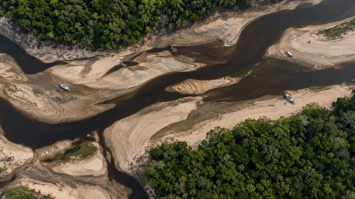 Vista aérea de rio amazônico durante a seca, com grandes bancos de areia e embarcações encalhadas