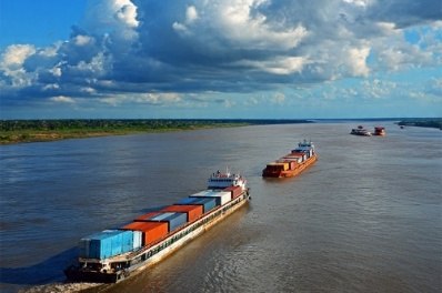 Comboio de balsas com contêineres navegando em rio da Amazônia