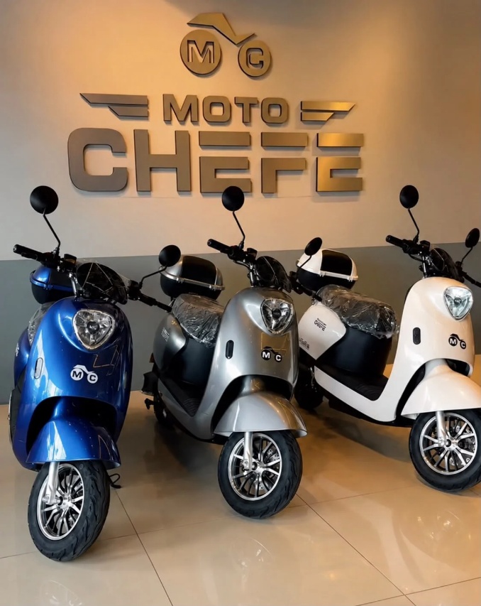 Três scooters elétricas MotoChefe expostas em loja, sob o letreiro da marca